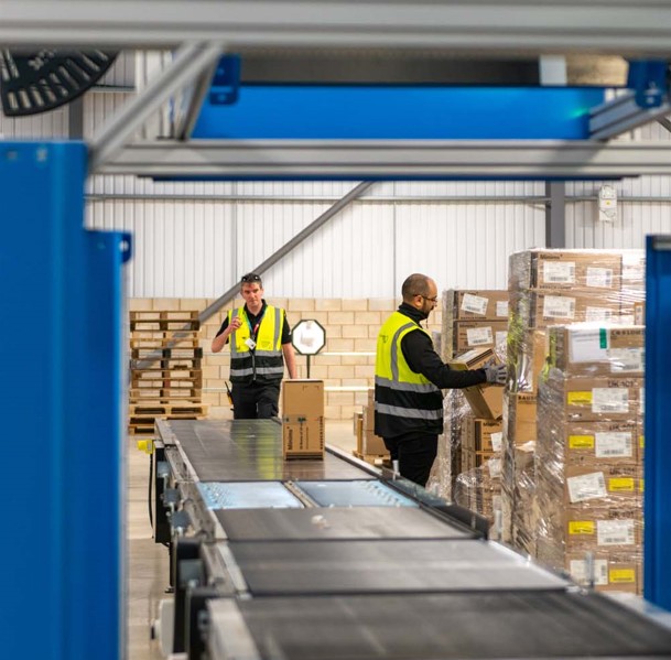 Two workers operating a conveyor belt in warehouse