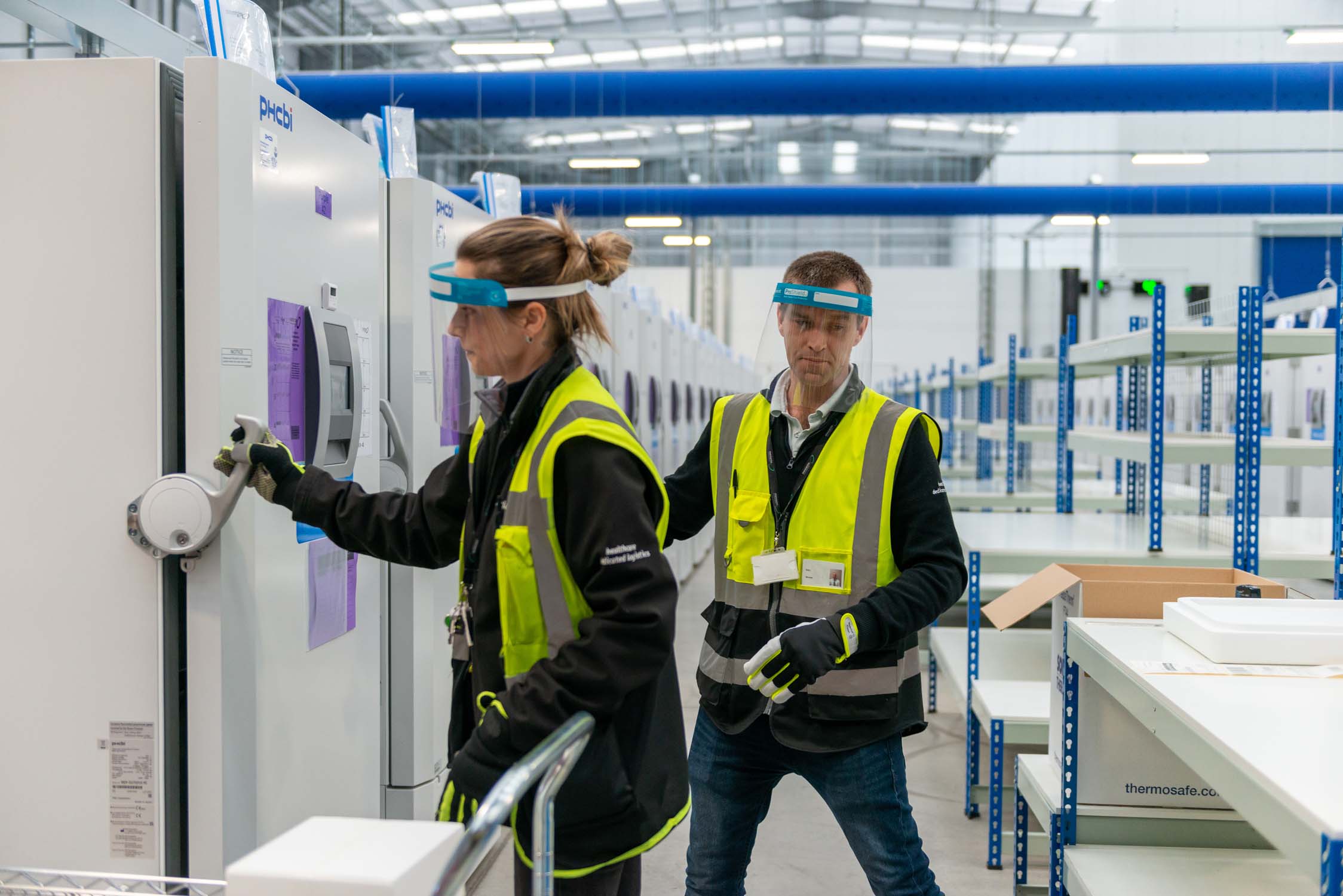 Two workers in safety vests working in the vaccine storage